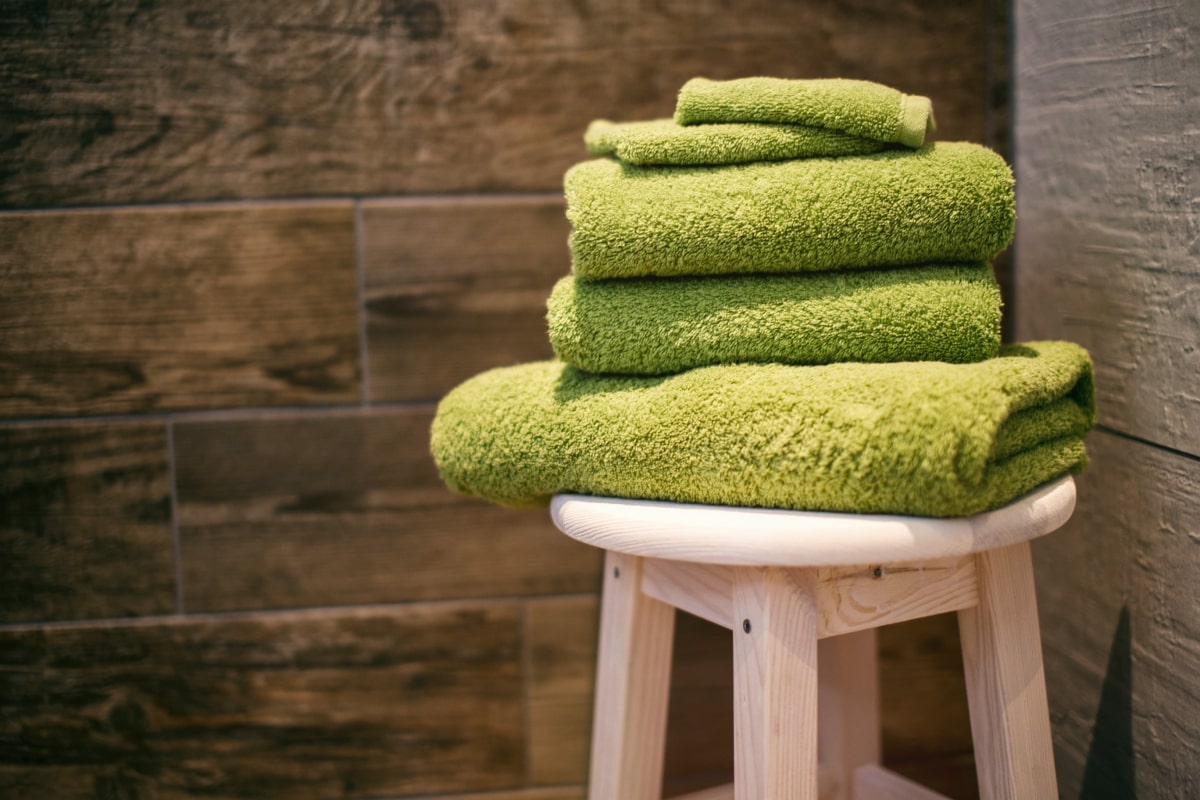 Folded towels stacked on a wooden stool against sauna panelling