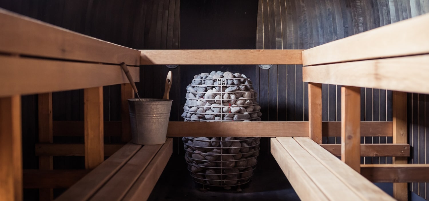 Inside a sauna: a stone-stacked heater between wooden benches